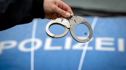 Ein Polizist hält ein Paar Handschellen.