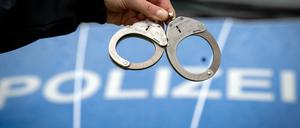 Ein Polizist hält ein Paar Handschellen. 