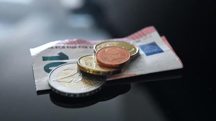 Münzen und ein Geldschein im Wert von 12,41 Euro liegen auf einer schwarzen Fläche (gestellte Szene). 