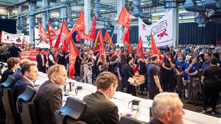 Mitarbeiter protestieren vor Beginn einer Betriebsversammlung in einer Halle im VW-Werk. 