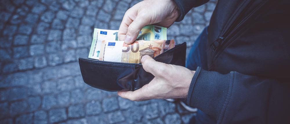 Brugge, Belgium - December 6, 2022: A man opens his wallet and holds 150 euro bills in his hand. Man with cash in hand *** Ein Mann öffnet seine Geldbörse und hält 150 Euro Geldscheine in seiner Hand. Mann mit Bargeld in der Hand
