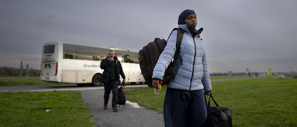 Eine Migrantin mit Kopftuch und dickem Wintermantel trägt ihre Habseligkeiten in das überfüllte Aufnahmezentrum, nachdem sie mit dem Bus in ter Apel im Nordosten der Niederlande angekommen ist.  