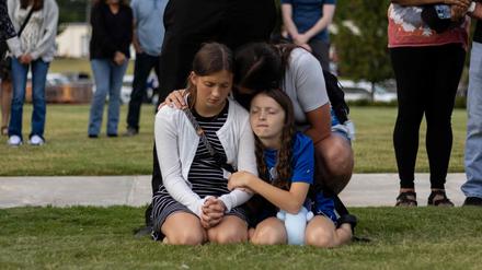 Eine Mutter und ihre Kinder verneigen sich im Gebet bei einer Mahnwache für die Opfer der Schießerei an der Apalachee High School im Jug Tavern Park in Winder, Georgia.