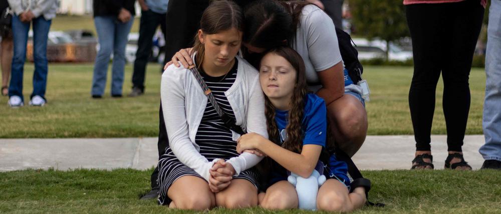 Eine Mutter und ihre Kinder verneigen sich im Gebet bei einer Mahnwache für die Opfer der Schießerei an der Apalachee High School im Jug Tavern Park in Winder, Georgia.