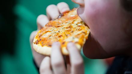 Ein Kind isst bei einem Kindergeburtstag Pizza.