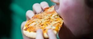 Ein Kind isst bei einem Kindergeburtstag Pizza.