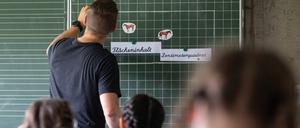 Ein Lehrer schreibt im Unterricht an einer Tafel.