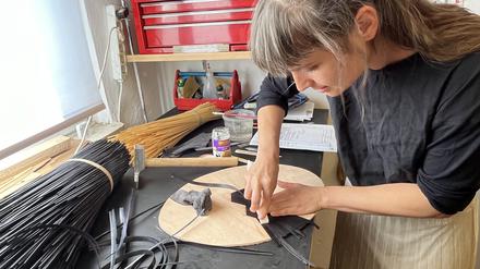 Tabea Vietzke, einige der wenigen Menschen in Berlin, die das Kunsthandwerk der Strohmarketerie beherrscht, bei der Arbeit. 