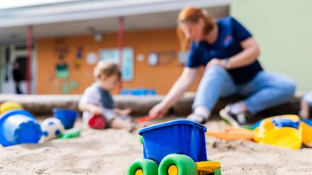 Ein Kind spielt mit einer Erzieherin im Sandkasten einer Kita. Bald könnte die Kita bestreikt werden.