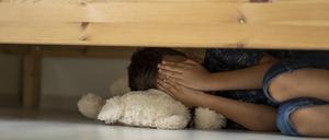 Ein Kind versteckt sich unter einem Bett (Symbolbild).