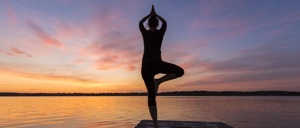 Frau übt die stehende Haltung Vrikshasana, Tree Pose, einbeinige Balancier Asana des mittelalterlichen Hatha Yoga.