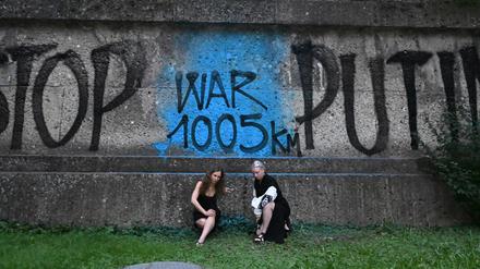 Die Künsterinnen Marija Wladimirowna Aljochina (l) und Taso Pletner, beide vom Künstlerkollektiv Pussy Riot, sitzen bei der Eröffnung der Ausstellung «Velvet Terrorism: Pussy Riot’s Russia» vor einem Graffiti mit dem Schriftzug «Stop Putin War1005km» am Haus der Kunst in München.