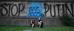 Die Künsterinnen Marija Wladimirowna Aljochina (l) und Taso Pletner, beide vom Künstlerkollektiv Pussy Riot, sitzen bei der Eröffnung der Ausstellung «Velvet Terrorism: Pussy Riot’s Russia» vor einem Graffiti mit dem Schriftzug «Stop Putin War1005km» am Haus der Kunst in München.