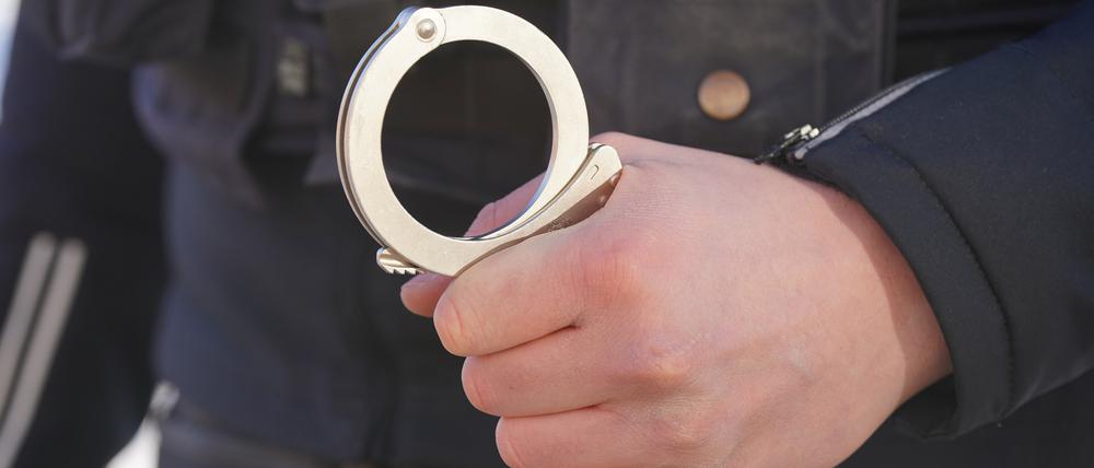 Ein Polizist hält Handschellen in der Hand.