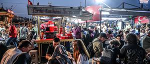 Menschen sitzen vor einem Stand und essen Fisch im Brot im Istanbuler Eminönü Hafen. (08.09.2024)
