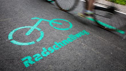 Radfahrer fahren nach der Eröffnung des Radschnellwegs zwischen Böblingen/Sindelfingen und Stuttgart an einer Aufschrift auf dem Asphalt vorbei.