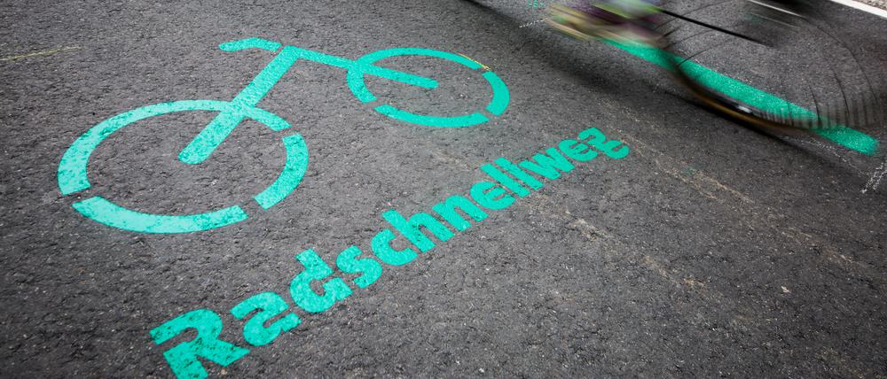 Radfahrer fahren nach der Eröffnung des Radschnellwegs zwischen Böblingen/Sindelfingen und Stuttgart an einer Aufschrift auf dem Asphalt vorbei.
