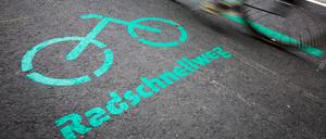 Radfahrer fahren nach der Eröffnung des Radschnellwegs zwischen Böblingen/Sindelfingen und Stuttgart an einer Aufschrift auf dem Asphalt vorbei.