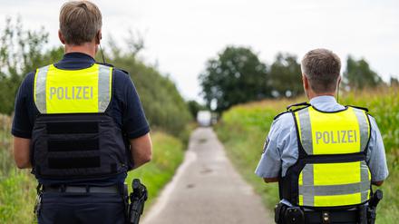 Polizeibeamte stehen am Rande eines Maisfeld.