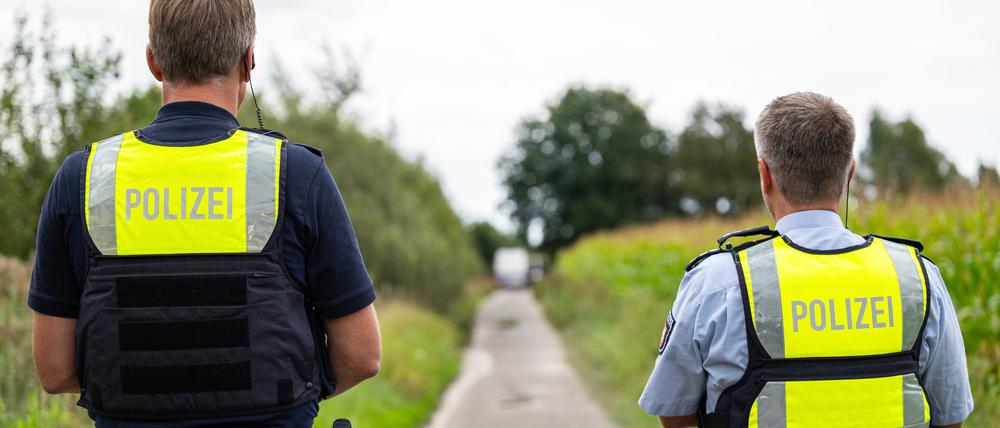 Polizeibeamte stehen am Rande eines Maisfeld.