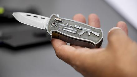 Ein Polizeibeamter hält ein sichergestelltes, verbotenes Springmesser in der Hand. (Symbolbild)