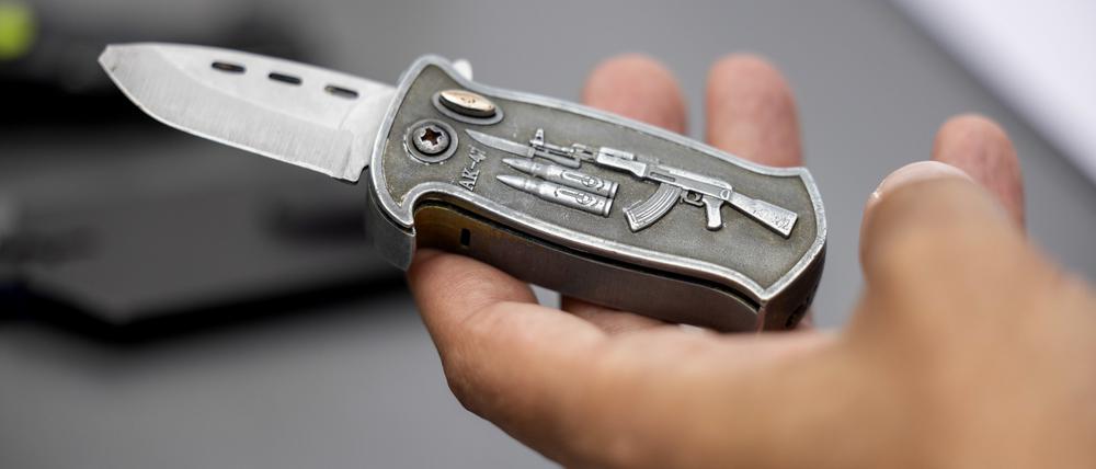 Ein Polizeibeamter hält ein sichergestelltes, verbotenes Springmesser in der Hand. (Symbolbild)