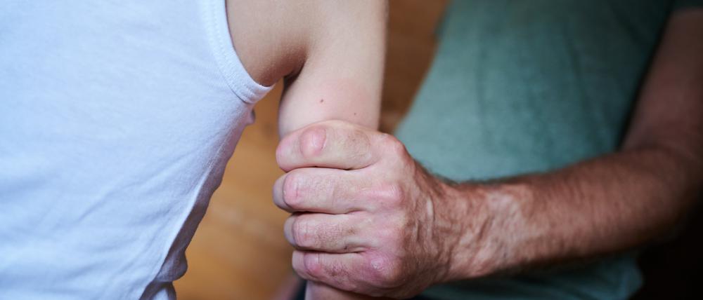 Ein Mann hält ein Kind fest am Arm.
