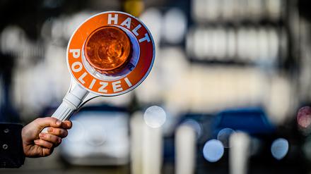 Ein Polizist hält eine Winkerkelle aus dem Einsatzwagen.