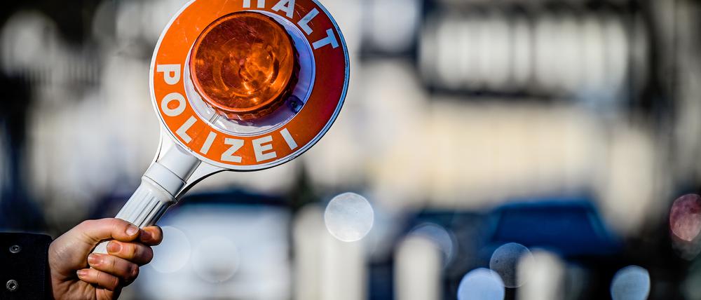 Ein Polizist hält eine Winkerkelle aus dem Einsatzwagen.