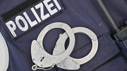 Auf einer Sicherheitsweste der Polizei liegen Handschellen und an der Seite ist ein Funkgerät zu erkennen.