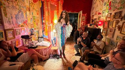 Die Malerin und Drag Queen Juwelia singt umgeben von Zuschauern in ihrer Salon-Galerie „Studio St. St.“ in Neukölln.