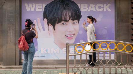 Fans posieren vor einem Plakat des BTS-Sängers Park Ji-min.
