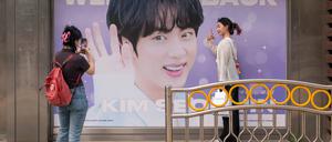 Fans posieren vor einem Plakat des BTS-Sängers Park Ji-min.
