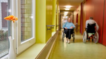 Bewohner im Rollstuhl auf dem Flur in einem Pflegeheim.