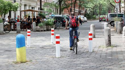 Ein Radfahrer fährt zwischen rot-weißen Pollern im Berliner Graefekiez.