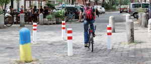 Ein Radfahrer fährt zwischen rot-weißen Pollern im Berliner Graefekiez.