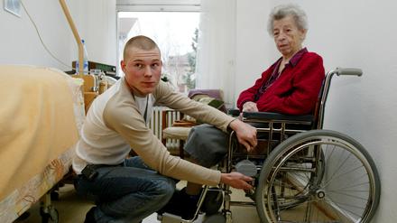 Ein Pfleger bei einer Bewohnerin eines Seniorenwohnheims: Viele Heime finden nicht genug Personal. 