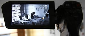 Eine Videokamera zeichnet in der gestellten Szene die Arbeit in einem Büro auf. 
