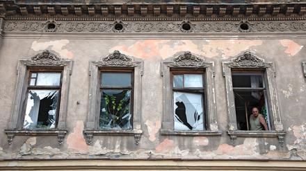 Ein Mann schaut in Lviv aus einem Haus, in dem die Fenster durch die Schockwelle eines Raketenangriffs zerstört worden sind.