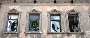 Ein Mann schaut in Lviv aus einem Haus, in dem die Fenster durch die Schockwelle eines Raketenangriffs zerstört worden sind.