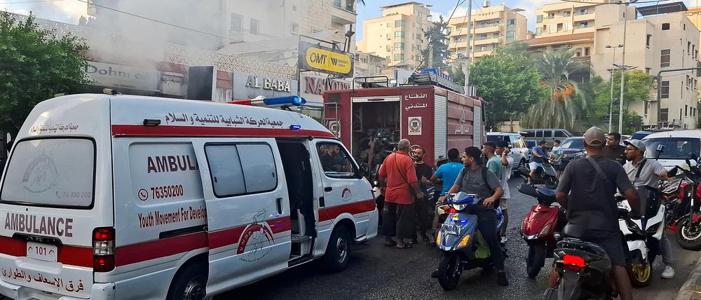 Menschen versammeln sich, als Rauch aus einem Geschäft in Sidon, Libanon, aufsteigt.