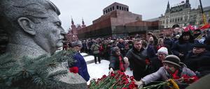 Russland, Moskau: Anhänger der kommunistischen Partei stellen sich am Grab von Josef Stalin, in der Nähe der Kremlmauer, auf, um anlässlich seines 71. Todestages Blumen niederzulegen. Im Hintergrund ist das Mausoleum des Sowjetgründers Wladimir Lenin zu sehen. Josef Stalin führte die Sowjetunion von 1924 bis zu seinem Tod im Jahr 1953.