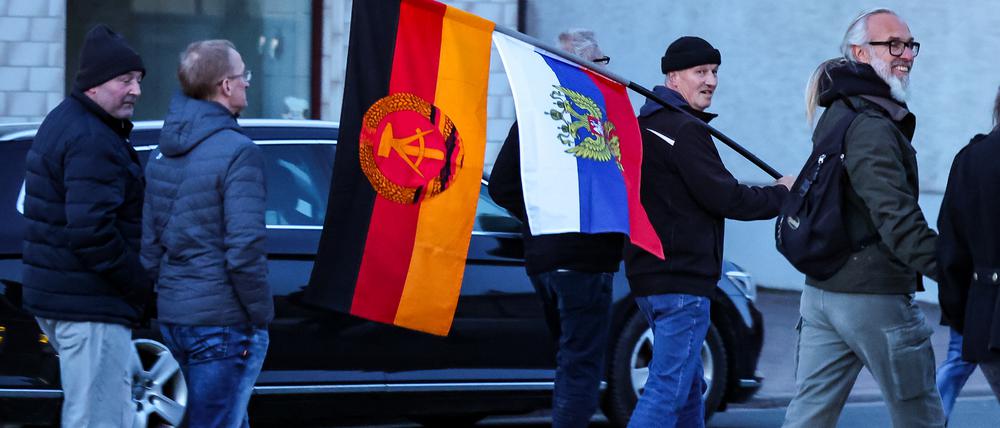Teilnehmer einer AfD-Demonstration gehen mit der Flagge der DDR und Russland durch die Kleinstadt.