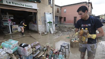 Nach anhaltenden Regenfällen und Überschwemmungen in der Region Emilia Romagna sammeln Menschen Waren aus einem Geschäft ein.
