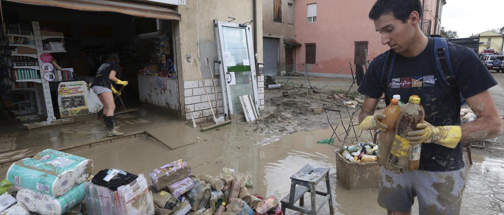 Nach anhaltenden Regenfällen und Überschwemmungen in der Region Emilia Romagna sammeln Menschen Waren aus einem Geschäft ein.