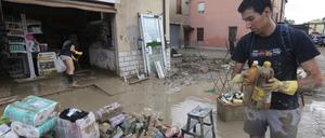 Nach anhaltenden Regenfällen und Überschwemmungen in der Region Emilia Romagna sammeln Menschen Waren aus einem Geschäft ein.
