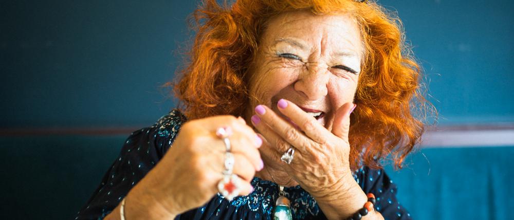 Eine alte Dame hält sich lachend eine Hand vor den Mund.