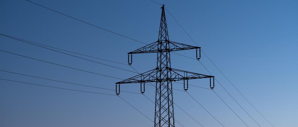 Ein Strommast ist bei Sonnenaufgang als Silhouette zu sehen. (Symbolbild)