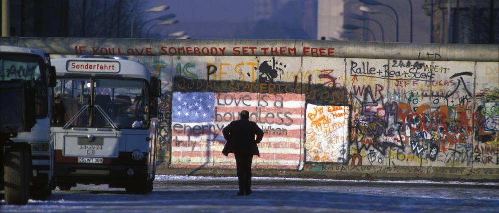 Ein Mann schaut auf die Berliner Mauer, 1986.