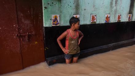 Ein Junge steht am inmitten einer überfluteten Straße in Kolkata, Indien.